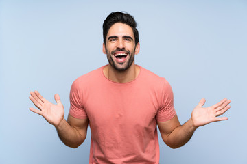 Naklejka premium Handsome young man in pink shirt over isolated blue background smiling a lot