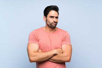 Handsome young man in pink shirt over isolated blue background making doubts gesture while lifting...