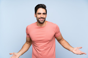 Fototapeta premium Handsome young man in pink shirt over isolated blue background smiling