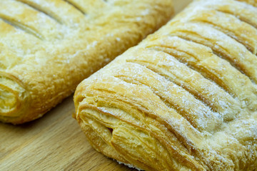 Puff pastries (puffs) with jam, sprinkled with icing sugar, on a wooden board