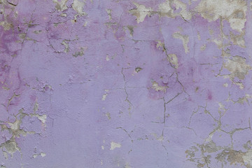 Grunge wall background with cracks and exfoliated old lilac plaster