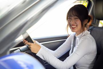 Asian women driving a car and smile happily with glad positive expression during the drive to travel journey, People enjoy laughing transport and relaxed happy woman on road trip vacation concept