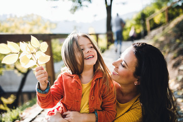 A portrait of young mother with a small daughter in autumn nature.