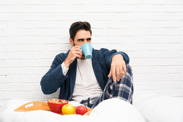 Man in bed with dressing gown and having breakfast