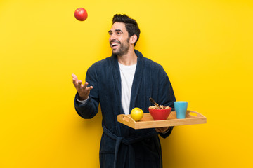 Handsome man in pajamas over isolated yellow wall