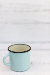 Enameled mugs in retro style on an old wooden background.