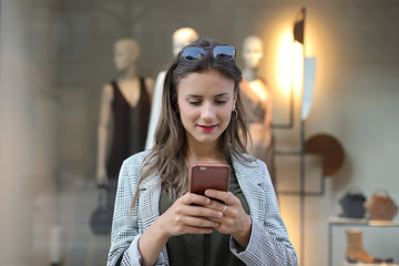 Young woman going shopping and using her phone to compare offers and prices online.