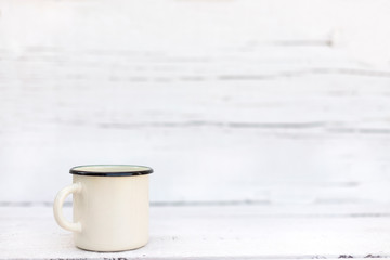 Enameled mugs in retro style on an old wooden background.