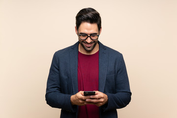 Handsome young man over isolated background sending a message with the mobile