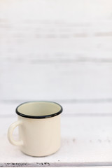 Enameled mugs in retro style on an old wooden background.