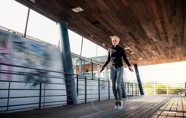 A young sportswoman doing exercise outdoors, skipping. © Halfpoint