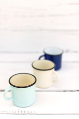 Enameled mugs in retro style on an old wooden background.