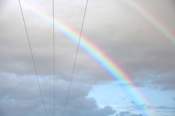 Kolorowa tęcza na tle chmór i przewodów elektrycznych. © Stanisław Błachowicz
