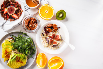 Vegan breakfast table with avocado toast, oatmeal, fruit, on white background.