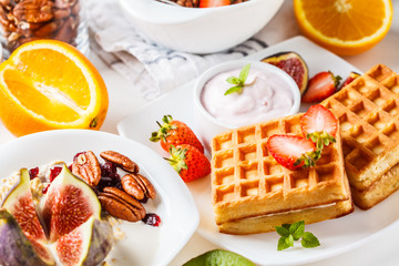 Breakfast table with oatmeal, waffles, croissants and fruits.