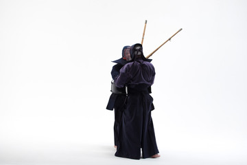 two Kendo martial arts fighters combat fighting in silhouette isolated on white bacground