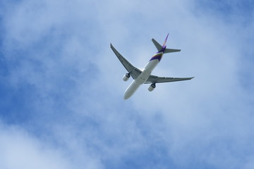 The plane is flying on the blue sky.