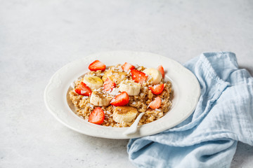 Oatmeal with banana, strawberries and peanut butter in white plate.