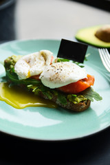 Hot toast with salmon, poached egg, herbs and avocado on a plate with a black copy space flag on a skewer