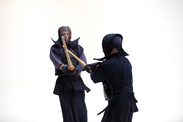 Two Kendo martial arts fighters combat fighting in silhouette isolated on white bacground