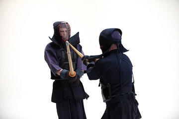 Two Kendo martial arts fighters combat fighting in silhouette isolated on white bacground