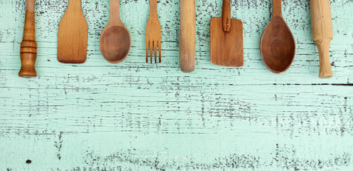 Vintage old kitchen utensils on a green wooden background.