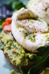 Close-up poached egg with yolk on toast with avocado and salad