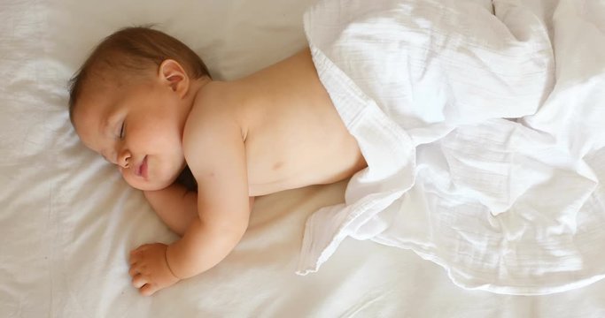 Peaceful adorable baby sleeping on his bed in a room at home. Soft focus. Sleeping baby concept. 1 year-old babyboy sleeps at home, top view