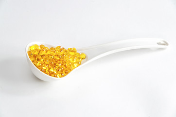 Fish oil capsules in a spoon on white bacground