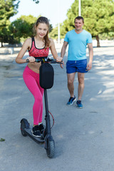 Fototapeta na wymiar Girl riding kick scooter with father