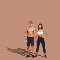 Fototapeta na wymiar Healthy couple with dumbbells on brown background with shadow on floor