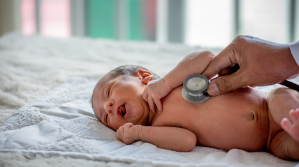 Soft blur of the doctor hands use stethoscope to check newborn baby health and take care him or...
