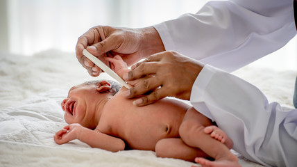 Obraz na płótnie Canvas Soft blur image of doctor hands use thermometer measure newborn baby temperature in the process of check up or treatment the baby.