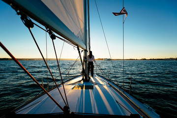 Rear view of woman standing on yacht at sunset