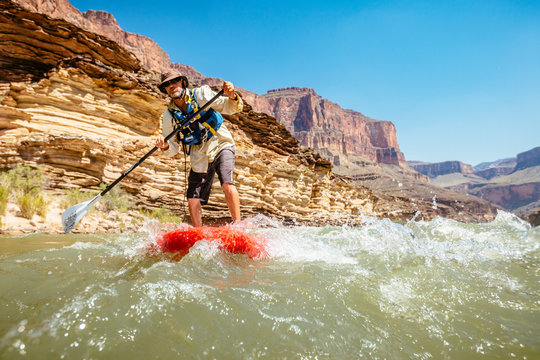 A man stand up paddleboards on the Colorado River, Grand Canyon National Park, Arizona, USA