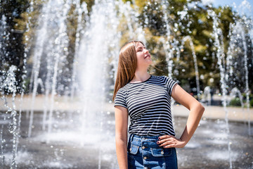 portrait of young happy attractive caucasian woman in casual clothes enjoying her time near fountain in the urban park