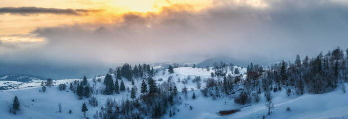 amazing panoramic view of rural village and mountains on horizon covered with snow on sunset. beautiful winter landscape