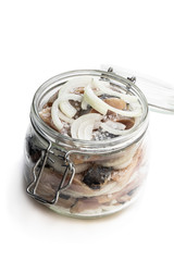 Sliced salted herring with onion in glass jar isolated on white