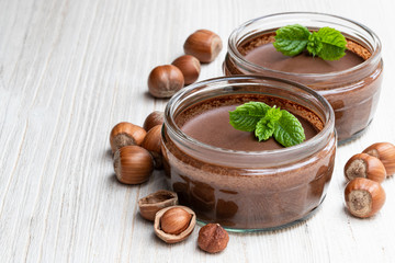 Homemade chocolate hazelnut praline in glass jar on white wooden table