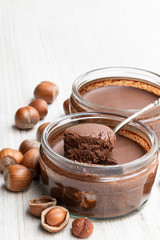 Homemade chocolate hazelnut praline in glass jar on white wooden table