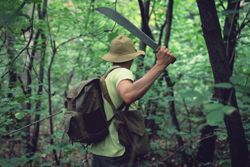 Tourist clears his way with a machete. - obrazy, fototapety, plakaty