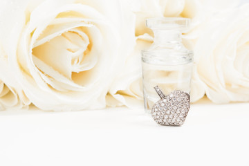 Obraz na płótnie Canvas Valentine's day gift with bouquet of white roses, fragrance and heart pendant with diamonds. Copy space