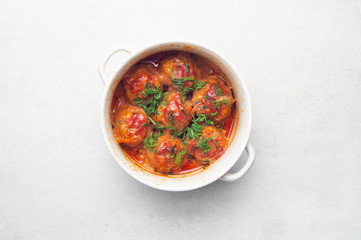 Meatballs stewed in tomato sauce with herbs in a saucepan