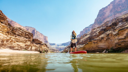 A man stand up paddleboards on the Colorado River, Grand Canyon National Park, Arizona, USA