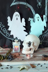 Skull, mystical decor, illumination, decorative lantern, autumn leaves on a wooden table, interior for Halloween, October