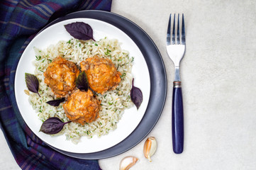 Meatballs and rice in a white and black plates with herbs and basil