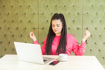 Time to relax! Successful young girl freelancer with black dreadlocks hairstyle in pink blouse are...
