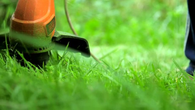 professional mower cuts grass with modern orange trimmer extreme slow motion. Concept outdoor housework