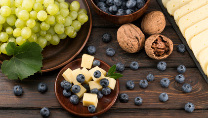 cheese with blueberries and grapes on a wooden background
