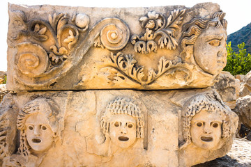 Part of the architecture of the ancient amphitheater. The architecture is located on the territory of modern Turkey. Several faces playing certain roles are carved on the stones.